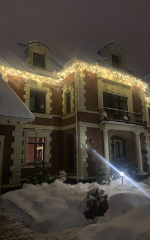 Новогоднее световое оформление фасада загородного дома в зимний вечер